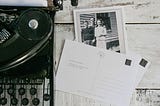 antique typewriter and postcards and polaroid on wooden surface