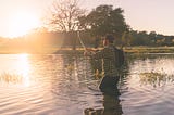 A man fishing while the sun is rising