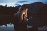 Girl reading off phone outside in dim lighting