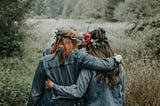 Two female friends walking with their arms around each other.