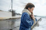 Sad young woman standing near water