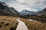 a wooden path leading up to mountains