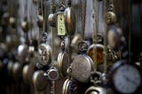 A wall of antique pocket watches to suggest time and people who run late.
