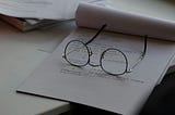 A pair of glasses laying on top of a notepad