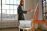 Artist in an airy studio painting on an easel.