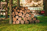 Logs stacked up against a tree.