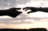 Image of two people’s outstretched hands almost grasping each other indicating the persons reaching out to each other.