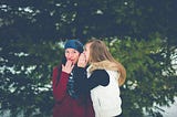 One teen girl is whispering to another teen girl.