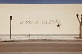 A wall with “No one is illegal” written on