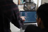 man in black and red plaid shirt using black and gray laptop computer