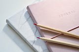 Pencils laid out on top of two notebooks.