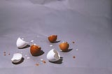 Brown and white, broken eggshells, scattered over the floor.