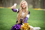 Gorgeous blond teenage cheerleader taking a selfie.
