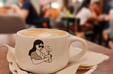 Single woman drinking coffee alone at a cafe full of people