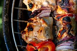 Close up of Meat and veggies on skewers set too cook on a barbeque grill