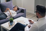 A patient in a therapy session lies on a couch and talks