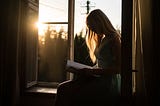 woman sat on a window sill reading