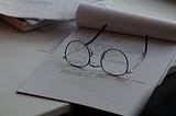 a pair of wire-rimmed glasses lying on a notepad