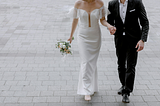 A bride and a groom holding hands outside.