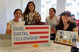 Our hackathon team in front of the “Civic Digital Fellowship” logo flag