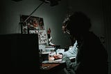 Girl writing by her desk under the light of a lamp