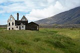 Abandoned shell of a house on an open windswept landscape.