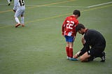 Football referee tying the laces of a young boy’s boots