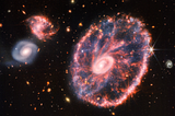 This new James Webb Telescope near and mid-infrared composite image highlights the Cartwheel Galaxy, the result of a high-speed collision that occurred about 440 million years ago, along with two neighboring galaxies.