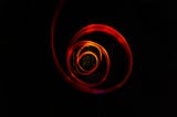 A vibrant red cloth twirling like a spiral before a black background