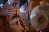 Buddhist monks in prayer with brass instrument