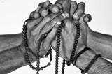 Two people embrace hands with beads around their wrists and symbolize unity, promise, commitment, connection.