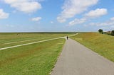 Vast, open landscape in the Schleswig-Holstein National Park Wattenmeer. A man walks along a dirt road. Northern Germany, Europe.