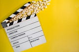 film slate on yellow background with popcorn