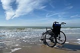 A wheelchair on a beach by the sea.