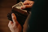 A man removing 1 dollar bills from a wallet