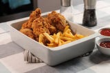 Fried chicken and French fries in a white baking dish