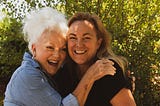 Two women hugging each other and smiling into the camera