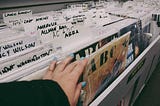 Vinyl records filed alphabetically, someone’s hand is picking out a record titled ABC.