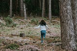 A girl running into the woods.