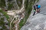 Mountain climber going down a rock face.