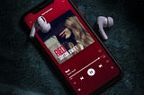 shows a mobile device and earbuds with Taylor Swift’s Red album playing