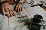 A close-up of a woman’s hands adding photos to her journal