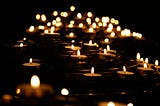 A field of small candles in a sea of black.