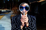 The LinkedIn Algorithm Explained — Photo of a girl with Shades holding a Magnifying Glass as a representation of people searching for a job.