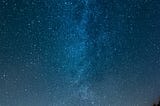 The night sky and a small lit village in the mountain range