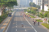 Dozens of cyclists use a wide five-lane road, taking over the street/ A bus is passing by in a protected and separated bus lane.