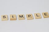 Scrabble letter blocks are lined up to spell “simple”