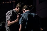 Three men huddled up together in shame