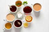 various cups of tea from black with milk to herbal with lemon on white background