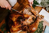 Close up of hands cutting a roasted turkey